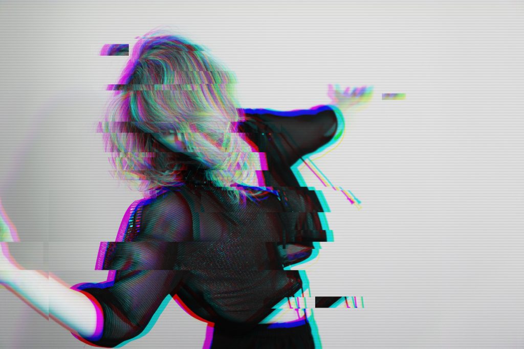 Dansfoto zwart-wit van Sharon Wesseling ze gaat met haar lichaam naar links, beweegt haar armen groots, vervaagde foto met een pixel filter eroverheen